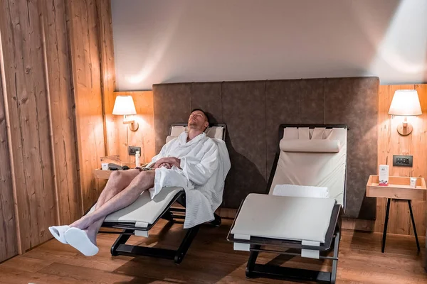 Man relaxing in luxurious hotel bedroom on reclining chair — Stock Photo, Image