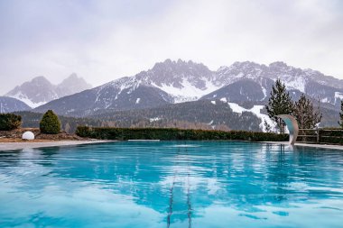 Karlı dağlara bakan yansımalı yüzme havuzu. Kış boyunca arka planda Alpler 'in manzarası. Lüks tatil beldesinden görüntü.