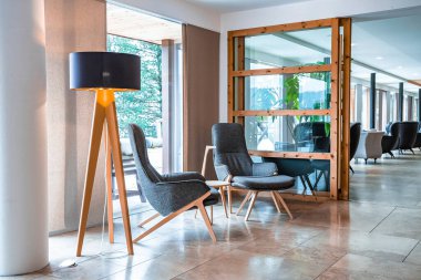Otel lobisinde lamba lamba koltukları dinleniyor. Lüks oteldeki boş oturma odaları cam camlara karşı. Tatil evindeki güzel dinlenme odasının içi..