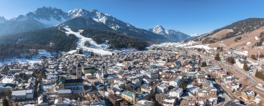 Güneşli bir günde kasabanın panoramik manzarası. Açık mavi gökyüzüne karşı karla kaplı dağlar. Alp bölgesinde kış boyunca manzara köyü.