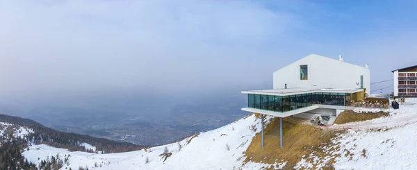 Alpine restaurant and museum on snow covered mountain. Panoramic view of converted funicular station on white landscape in alps . Beautiful tourist attraction against sky during winter.