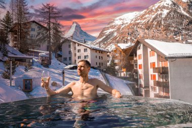 Adam şehir manzarasına karşı havuzda yüzerken şaraptan zevk alıyor. Madde boynuzu dağına karşı jakuzide dinlenen bir turist. Gün batımında karla kaplı manzara.