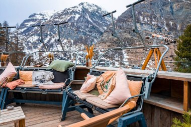 Zermatt, İsviçre. 15 Mart 2022. Banklarda renkli yastıklar. Majestic dağlarına karşı açık alan. Alp bölgesinde kış boyunca lüks bir kayak merkezindedir..