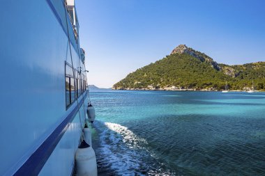 Denizde hareket eden yolcu teknesinin kırpılmış görüntüsü. Açık mavi gökyüzüne karşı güzel bir uçurum manzarası. Yaz boyunca deniz turizmi kavramı