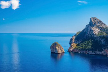 Kayalık uçurum ve Akdeniz manzaralı. Güneşli bir günde adadaki dağın resimli görüntüsü. Yazın gökyüzüne karşı güzel mavi okyanus.