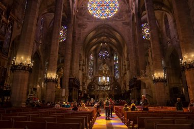 Mallorca, İspanya. 27 Nisan 2022. Turistler güzel Gotik La Seu Katedrali 'ni ziyaret edip dua ediyorlar. Şehirdeki ortaçağ kilisesinde leke camlar ve sıralar vardı. Tarihi dini bir yerin içinde.