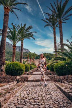 Çiçeklerin arasında yürürken gözlerini kaçıran dişi turistler. Gündelik giyinmiş bir kadın tarihi parkı gökyüzüne karşı keşfediyor. O, adada yaz tatilinin tadını çıkarıyor..