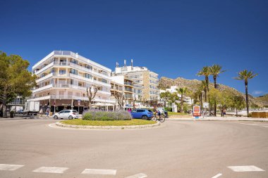 Mallorca, İspanya. 27 Nisan 2022. Araçlar binalarla dolambaçlı yoldan ilerliyorlar. Açık mavi gökyüzüne karşı şehrin caddesindeki bitkilerin manzarası. Yaz boyunca şehirde oteller.