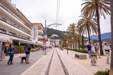 Mallorca, İspanya. 27 Nisan 2022. Binaların ve palmiye ağaçlarının arasında demiryolu izleri var. Eski tarihi kenti keşfeden turistler. Şehirde demiryolu rayları olan cadde azalıyor.