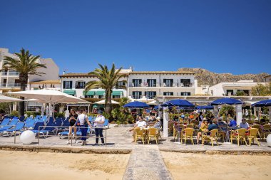 Mallorca, İspanya. 27 Nisan 2022. Turistler açık hava restoranında dinleniyor. İnsanlar boş zamanlarını açık mavi gökyüzüne karşı kumlu sahilde geçiriyorlar. Yaz tatilinin tadını çıkarıyorlar..