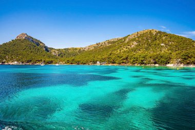 Akdeniz 'deki kayalık uçurumun manzarası. Yaz boyunca güzel turkuaz renkli okyanus. Mavi gökyüzüne karşı İdealist bir ada manzarası.
