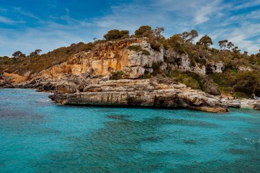 Güzel denizdeki kayalık uçurumlardaki ağaçların manzarası. Gökyüzüne karşı Idyllic Akdeniz Okyanusu. Yaz boyunca turkuaz suyu olan ada..