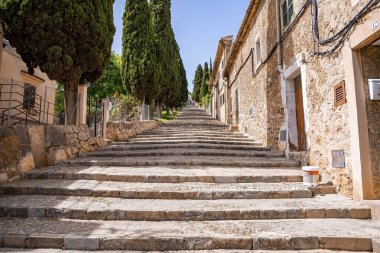 Şehirdeki eski kiliseye giden merdivenlerin alçak açılı görüntüsü. Ağaçların ve binaların arasında merdivenlerde yürüyen turistler. Yazın açık gökyüzüne karşı tarihi evler.
