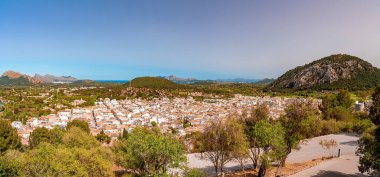Panoramic view of townscape and trees against mountains. High angle view of beautiful landscape against clear blue sky. Urban nature during sunny day.