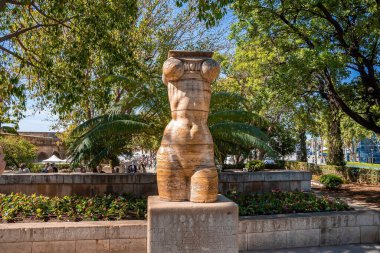 Ağaçlara ve bitkilere karşı kadın heykeli. Tarihi parkta heykel. Eski kasabadaki doğanın yaratıcı cazibesi.
