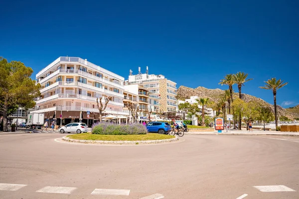 Mallorca, İspanya. 27 Nisan 2022. Araçlar binalarla dolambaçlı yoldan ilerliyorlar. Açık mavi gökyüzüne karşı şehrin caddesindeki bitkilerin manzarası. Yaz boyunca şehirde oteller.