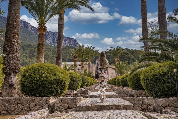 Çiçeklerin arasında yürüyen kadın turistler. Günlük giyinmiş bir kadın tarihi parkı keşfediyor. Yaz tatilini adada geçiriyor..