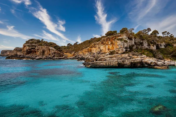 Akdeniz 'deki kayalık uçurumlardaki ağaçların manzarası. Mavi gökyüzüne karşı güzel okyanus. Yaz boyunca cennet gibi bir ada manzarası.