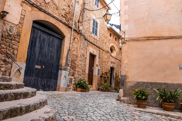 Eski evin dışında saksı bitkileri. İkamet bölgesindeki binaların arasında kaldırımlı bir cadde. Yaz boyunca tarihi kentte seyahat kavramı.
