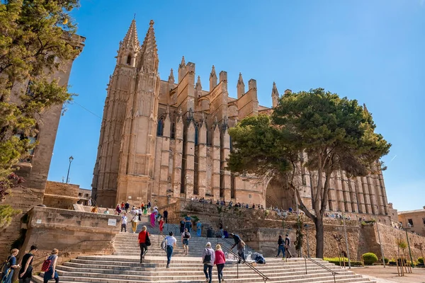 Mallorca, İspanya. 27 Nisan 2022. Şehirdeki La Seu katedralini ziyaret eden turistler. Ortaçağ kilisesinin açık mavi gökyüzüne karşı düşük açılı görüntüsü. Yaz boyunca tarihi kentte ünlü bir eğlence..