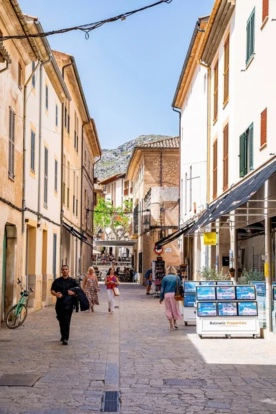 Mallorca, İspanya. 27 Nisan 2022. Turistler ara sokakta binaların arasında yürüyorlar. Açık mavi gökyüzüne karşı yerleşim bölgesindeki sokağa düşen gölge. Yaz tatilinde turizm.