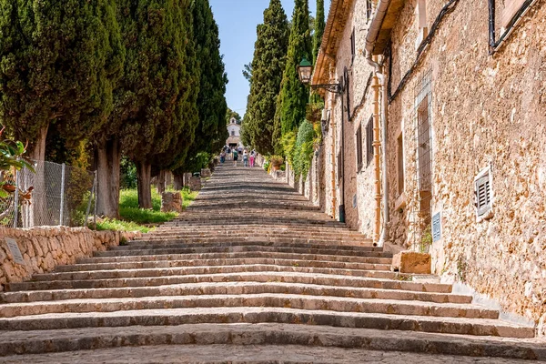 Ağaçların ve binaların arasında yürüyen turistlerin alçak açılı görüntüsü. Merdivenler kasabadaki eski kiliseye doğru gidiyor. Yaz boyunca gökyüzüne karşı tarihi yerleşim bölgesi.