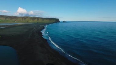 Reynisfjara Vik 'te büyük dalgaları olan İzlanda siyah kumsalı. Hava sineması 4K videosu. Güzel İzlanda doğa kıyısı yukarıdan.