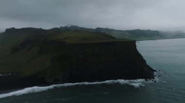 Reynisfjara Vik 'te büyük dalgaları olan İzlanda siyah kumsalı. Hava sineması 4K videosu. Güzel İzlanda doğa kıyısı yukarıdan.