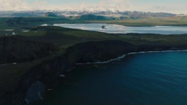 Reynisfjara Vik 'te büyük dalgaları olan İzlanda siyah kumsalı. Hava sineması 4K videosu. Güzel İzlanda doğa kıyısı yukarıdan.
