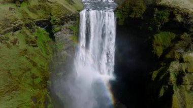 Gökkuşaklı ünlü Skogafoss şelalesi. Gün batımında İzlanda 'nın dramatik manzarası. Renkli gökyüzü manzaralı görkemli Skogafoss Şelalesi kırsalda.
