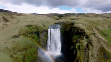 Gökkuşaklı ünlü Skogafoss şelalesi. Gün batımında İzlanda 'nın dramatik manzarası. Renkli gökyüzü manzaralı görkemli Skogafoss Şelalesi kırsalda.
