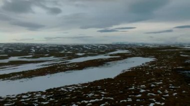 Boş lav tarlalarının ve Snaefellsjokull yakınlarındaki buzla kaplı devasa volkanik dağın havadan çekilmiş videosu, İzlanda.