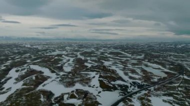 Boş lav tarlalarının ve Snaefellsjokull yakınlarındaki buzla kaplı devasa volkanik dağın havadan çekilmiş videosu, İzlanda.