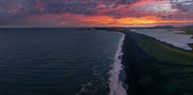 Reynisfjara Vik 'te büyük dalgaları olan İzlanda siyah kumsalı. Hava sineması 4K videosu. Güzel İzlanda doğa kıyısı yukarıdan.