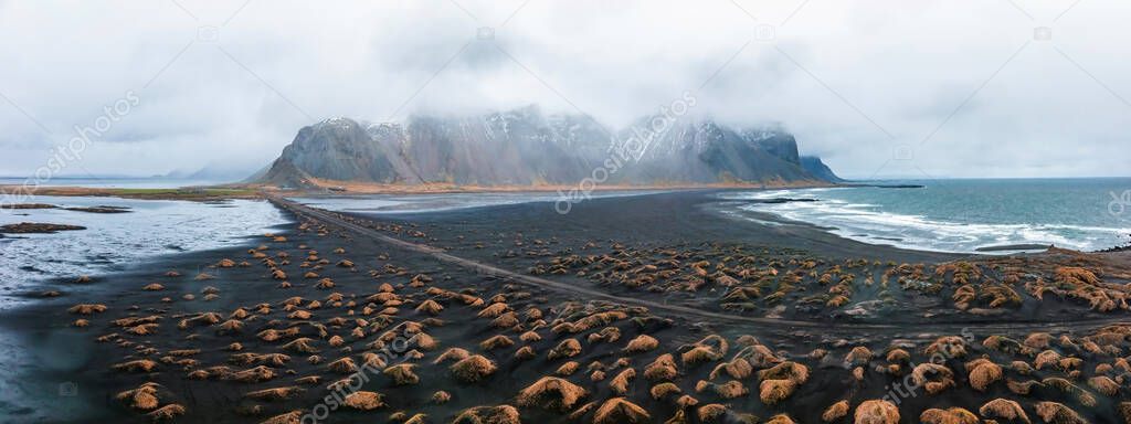 Aerial view of the impressive colorful seascape of Iceland. Wonderful picturesque Scene near Stokksnes cape and Vestrahorn Mountain, Black sand dunes on a rainy windy day.