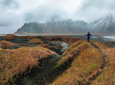 Stokksnes Burnu ve İzlanda 'daki Vestrahorn Dağı yakınlarında fırtınalı İzlanda' yı keşfeden genç bir kız..