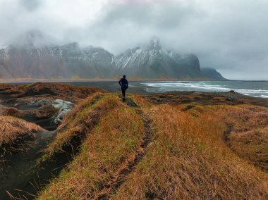 Stokksnes Burnu ve İzlanda 'daki Vestrahorn Dağı yakınlarında fırtınalı İzlanda' yı keşfeden genç bir kız..