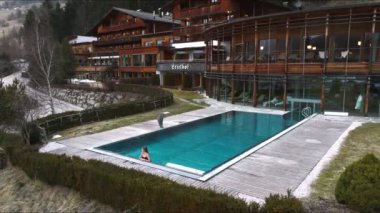 Lüks otelin havuz manzarası. Açık havada sonsuz havuzu var. Havuzun kenarında dinlenen genç bir bayan var..