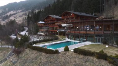 Lüks otelin havuz manzarası. Açık havada sonsuz havuzu var. Havuzun kenarında dinlenen genç bir adam var..