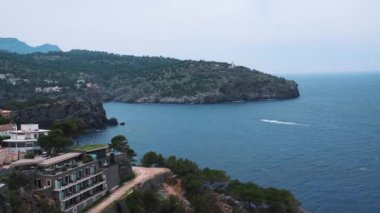 Güzel Akdeniz 'in yüksek açılı manzarası. Sahildeki kayalık uçurumun manzarası. Yazın bulutlu gökyüzüne karşı adanın masmavi denizi.