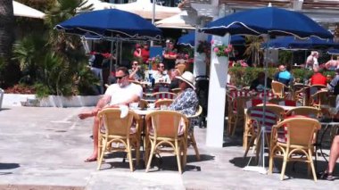 Turistler açık hava restoranında eğleniyor. Arkadaşlar ve aile dağların yakınındaki kumsalda dinleniyor. İnsanlar Mallorca adasında yaz tatilinin tadını çıkarıyorlar..