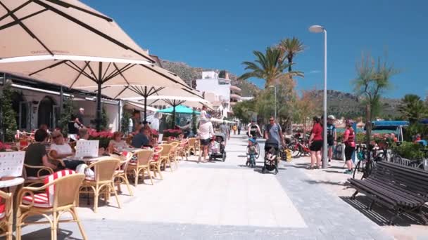 アウトドアレストランで楽しむ観光客 山の近くの砂浜でリラックスしている友人や家族 マヨルカ島で夏休みを楽しむ人々 — ストック動画
