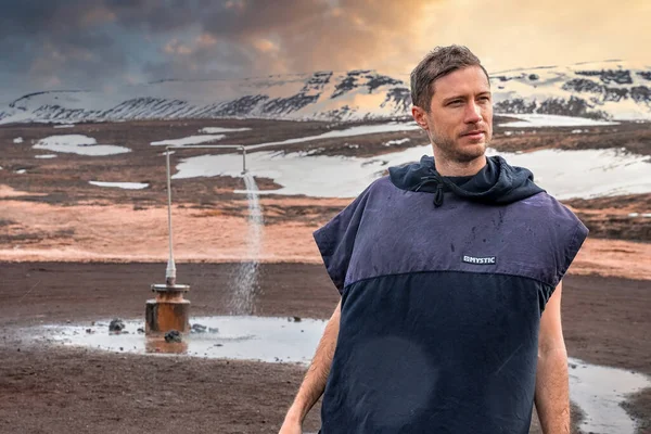 在克拉弗拉 一个有远见的游客从地热发电的地热淋浴站向远方望去 穿着雨衣的男性旅行者在白雪覆盖的高山上行走 他正在探索著名的景点 — 图库照片