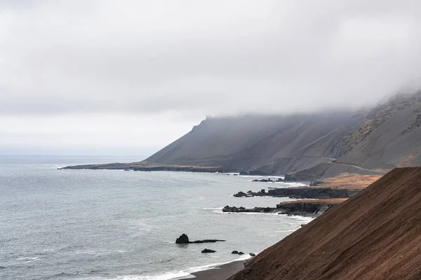 急な茶色の斜面の高角度ビュー 黒砂のビーチで曇りの空に対して急いで海の波の風景 霧の多い天気の間の火山谷の美しい景色 — ストック写真