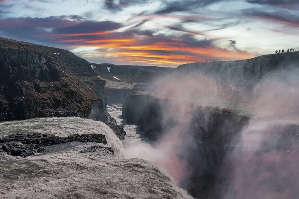 Altın Çember 'deki Gullfoss şelalesinin güzel manzarası. Bulutlu gökyüzüne düşen su manzarası. Gün batımında vadideki kaya oluşumları arasında çağlayanların resimli manzarası..