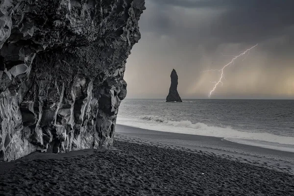Scenic view of lightning at Reynisfjara Beach. Beautiful basalt column rock formations at black sand seashore. Idyllic view of cliff at famous tourist attraction during stormy night.