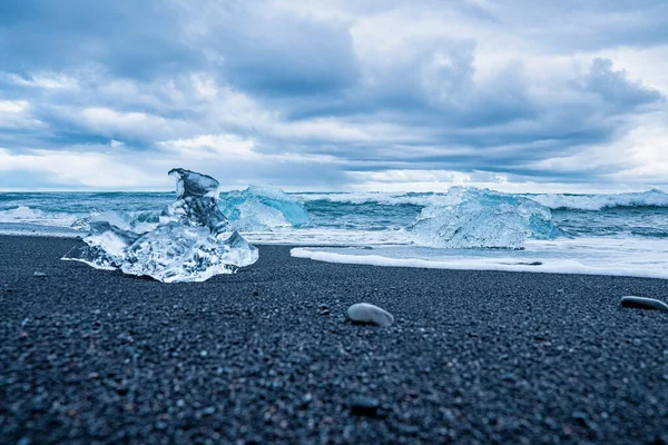 钻石海滩黑色沙滩上美丽的冰山的特写 在多云的天空中 朱库尔沙隆冰川泻湖的浮冰块 海浪冲向海岸的场景 — 图库照片