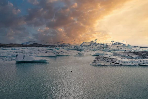曇り空に対するジョクルサロン氷河ラグーンの景色 冷たい水の中に浮かぶ氷河の氷の形成の美しい景色 日没時の凍結した氷山の牧歌的な風景 — ストック写真