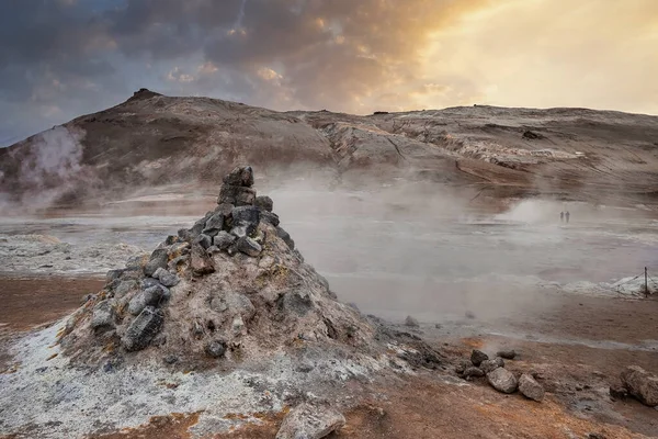 View of steaming fumarole in geothermal area of Hverir. Sulphur dioxide emitting from volcanic crater at Namafjall during sunset. View of geyser in famous tourist attraction against sky.