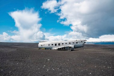 Kara Kumsal 'da uçak enkazı. Ünlü turistik mekanın manzarası. Solheimasandur 'da bulutlu gökyüzüne karşı terk edilmiş hasarlı uçak.